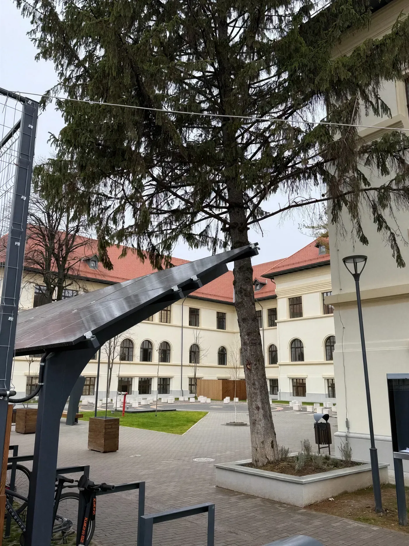 Canopia fotovoltaică văzută din curtea colegiului, cu clădirea în fundal